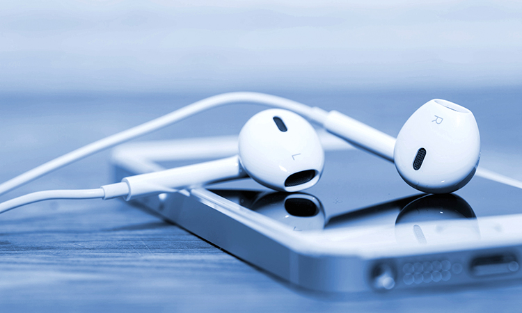 White earbud headphones draped across a smartphone