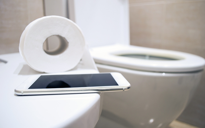Toilet with toilet paper and an iPad