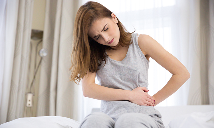 A young woman clutching her stomach in pain
