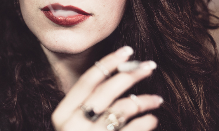 Woman holding cannabis joint and while smoke emits after she inhales