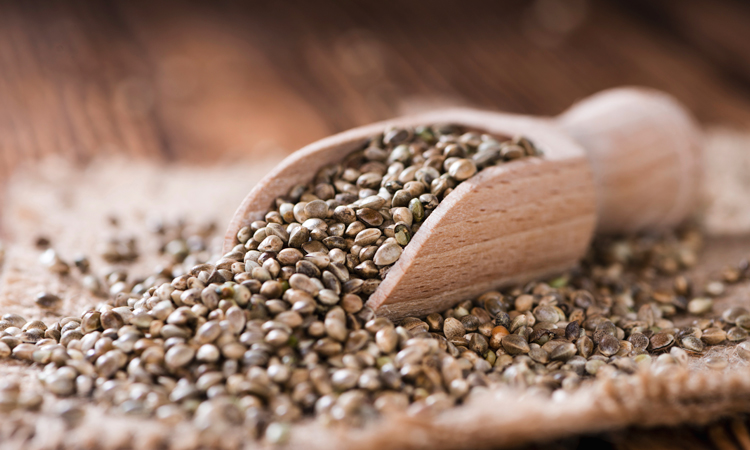 weed seeds in wooden spoon on hemp doily