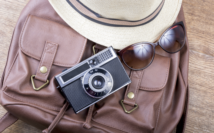 Purse with a camera, hat, and sunglasses
