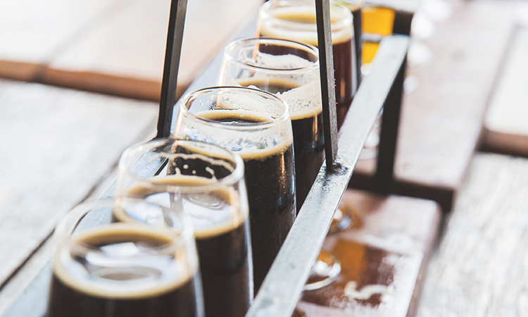 A flight of beers on a table arranged from dark to light brew